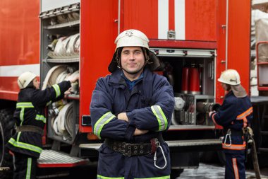 İtfaiyeci (itfaiye) eylem daimi bir firetruck yakınındaki. Acil durum Emanet. Koruma, tehlikeden kurtarmak.