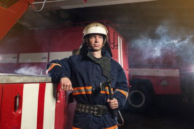 İtfaiyeci (itfaiye) eylem daimi bir firetruck yakınındaki. Acil durum Emanet. Koruma, tehlikeden kurtarmak.