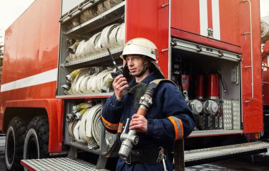 İtfaiyeci (itfaiye) eylem daimi bir firetruck yakınındaki. Acil durum Emanet. Koruma, tehlikeden kurtarmak.