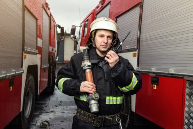 İtfaiyeci (itfaiye) eylem daimi bir firetruck yakınındaki. Acil durum Emanet. Koruma, tehlikeden kurtarmak.