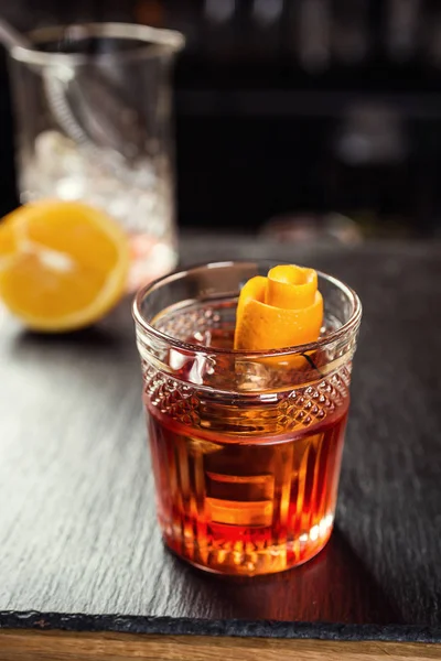 Verre de whisky (cognac ou brandy) avec citron et glaçons debout sur le comptoir du bar avec une bouteille sur le fond — Photo