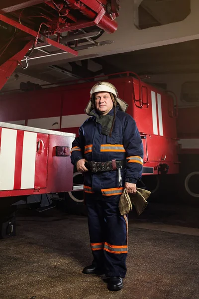 Brandweerman (brandweerman) in actie staande in de buurt van een brandweerwagen. De veiligheid van de noodsituatie. Bescherming, redding van gevaar. — Stockfoto