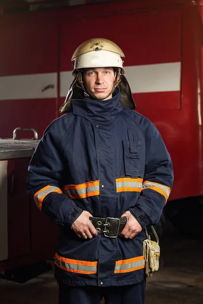 Brandweerman (brandweerman) in actie staande in de buurt van een brandweerwagen. De veiligheid van de noodsituatie. Bescherming, redding van gevaar. — Stockfoto