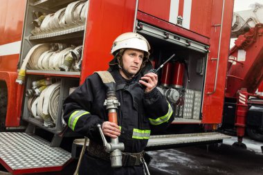 İtfaiyeci (itfaiye) eylem daimi bir firetruck yakınındaki. Acil durum Emanet. Koruma, tehlikeden kurtarmak.