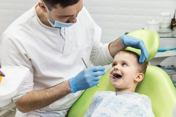 Dentysta badanie zębów małego chłopca w klinice. Wystąpienia problemów stomatologicznych. — Zdjęcie stockowe