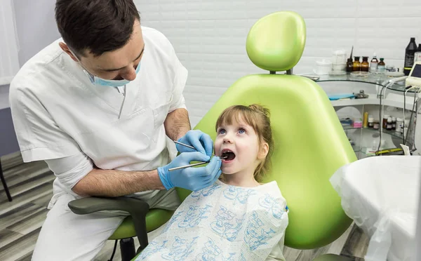 Dentysta, badając mała dziewczynka zębów w klinice. Wystąpienia problemów stomatologicznych. — Zdjęcie stockowe