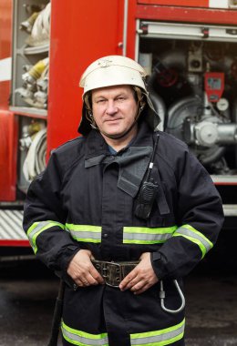 İtfaiyeci (itfaiye) eylem daimi bir firetruck yakınındaki. Acil durum Emanet. Koruma, tehlikeden kurtarmak.