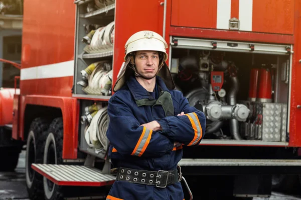 Brandweerman (brandweerman) in actie staande in de buurt van een brandweerwagen. De veiligheid van de noodsituatie. Bescherming, redding van gevaar. — Stockfoto