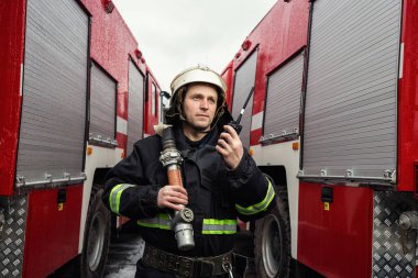 İtfaiyeci (itfaiye) eylem daimi bir firetruck yakınındaki. Acil durum Emanet. Koruma, tehlikeden kurtarmak.