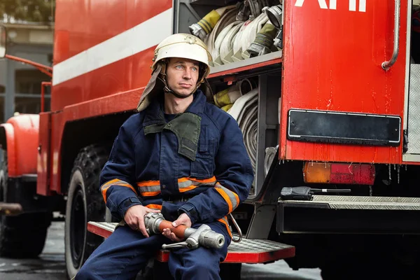 Strażak (strażak) w akcji stojący w pobliżu wóz strażacki. Awaryjnych bezpieczeństwa. Ochrony, ratunek przed niebezpieczeństwem. — Zdjęcie stockowe