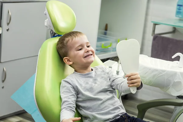 Kid boy in dentist\'s chair looks in the mirror. Dental problem.