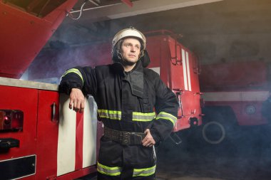 İtfaiyeci (itfaiye) eylem daimi bir firetruck yakınındaki. Acil durum Emanet. Koruma, tehlikeden kurtarmak.