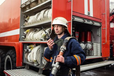 İtfaiyeci (itfaiye) eylem daimi bir firetruck yakınındaki. Emer