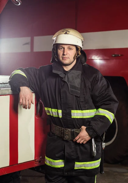 Strażak (strażak) w akcji stojący w pobliżu wóz strażacki. Emer — Zdjęcie stockowe