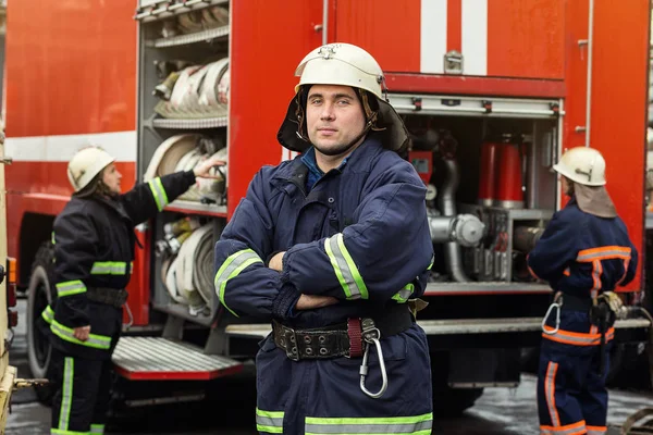 Brandweerman (brandweerman) in actie staande in de buurt van een brandweerwagen. Emer — Stockfoto