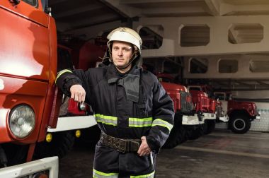 İtfaiyeci (itfaiye) eylem daimi bir firetruck yakınındaki. Emer