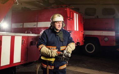 İtfaiyeci (itfaiye) eylem daimi bir firetruck yakınındaki. Acil durum Emanet. Koruma, tehlikeden kurtarmak.