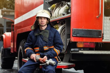 İtfaiyeci (itfaiye) eylem daimi bir firetruck yakınındaki. Acil durum Emanet. Koruma, tehlikeden kurtarmak.