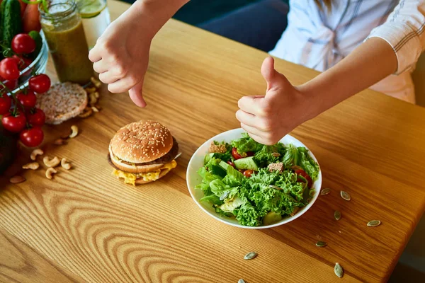 Женщина отказывается есть нездоровый гамбургер. Дешевая вредная пища против здорового питания Лицензионные Стоковые Изображения
