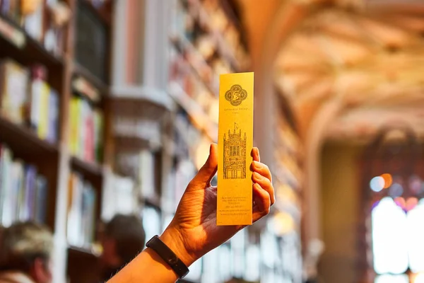 Туристические руки держат закладку для книги в библиотечном книжном магазине Livraria Lello в историческом центре Порту, знаменитом фильмом о Гарри Поттере . — стоковое фото