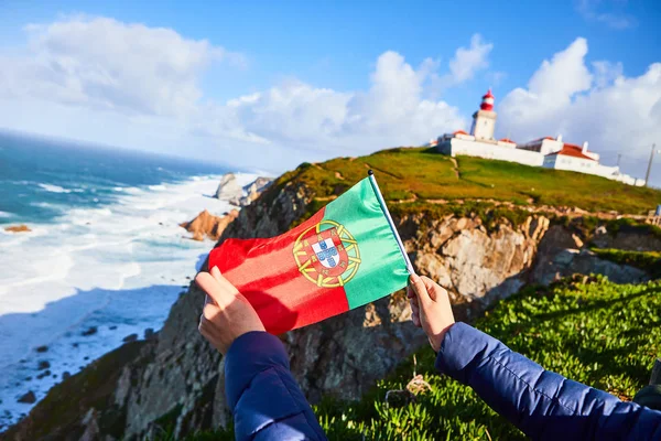 Jonge vrouw toerist op Cape Cabo da Roca met de vlag van Portugal met uitzicht op prachtige landschap, wintertocht. Westste punt van Europa — Stockfoto