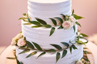 Çok katlı düğün pastası beyaz tonda süslenmiş güzel çiçeklerle