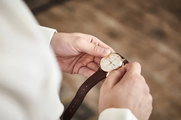 Geschäftsmann, der die Uhrzeit an seiner Armbanduhr kontrolliert, Mann, der die Uhr an der Hand hält, Bräutigam, der sich morgens vor der Trauung fertig macht. Männermode — Stockfoto