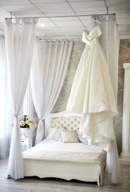 Güzel gelinlik odada asılı, kadın törenden önce hazırlanıyor.