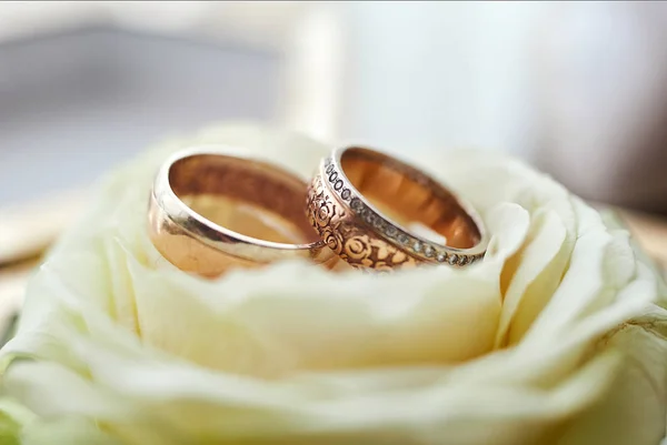 wedding rings lie on the table near a wedding bouquet