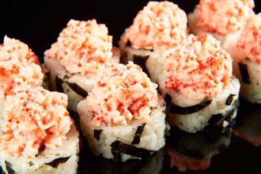 Geleneksel suşi rulosu füme yılan balığı, krem peynir, havyar ve siyah taşın üzerinde avokado. Japon yemeği.