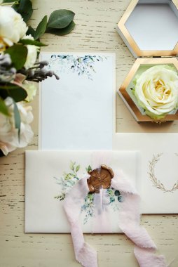 Ayakkabı, buket, yüzük ve davetiye kartları gibi düğün aksesuarları masanın üzerinde.