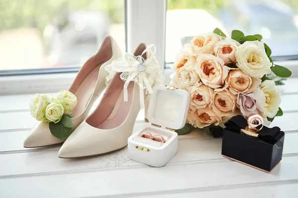 bridal accessories such as shoes, bouquet , ring and perfume lie on a table