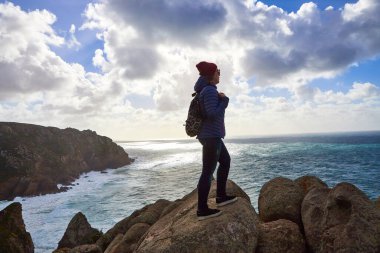 Cabo da Roca Burnu 'nda genç bir turist uçurumun kenarında duruyor. Okyanusun dalgaları uçurumun dibindeki kayalarda kırılıyor.