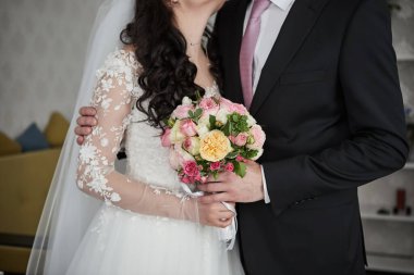 Gelin elinde bir buket ile damadın yanında duruyor.