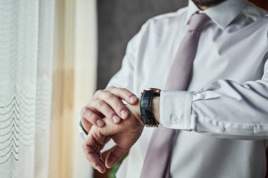 İş adamı kol saatini kontrol ediyor, saati eline alıyor, damat düğün töreninden önce hazırlanıyor. Erkekler Moda