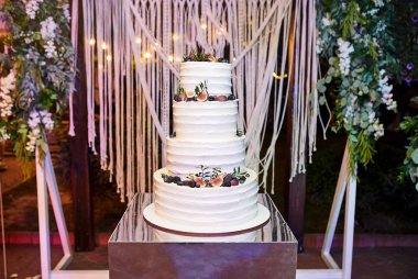 Çok katlı düğün pastası beyaz tonda süslenmiş güzel çiçeklerle