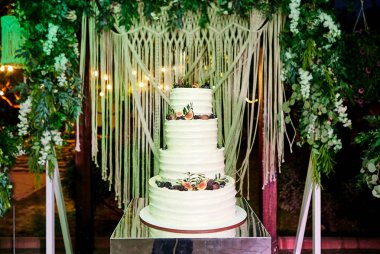 Çok katlı düğün pastası beyaz tonda süslenmiş güzel çiçeklerle