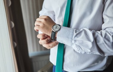 İş adamı kol saatini kontrol ediyor, saati eline alıyor, damat düğün töreninden önce hazırlanıyor. Erkekler Moda