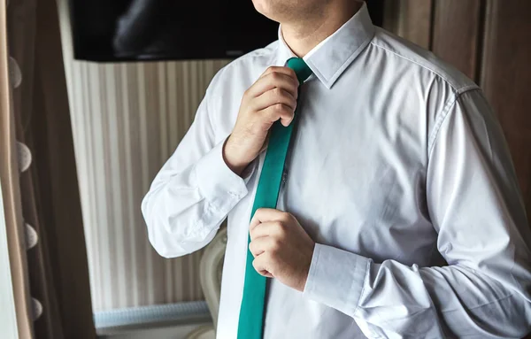 man in shirt dressing up and adjusting tie on neck at home. Men Fashion