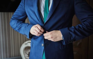 İş adamı ceket giyiyor, erkek eli kapalı, damat düğün töreninden önce hazırlanıyor.