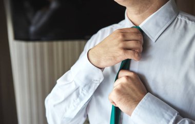 Gömlekli bir adam evde kravat takıyor. Erkekler Moda