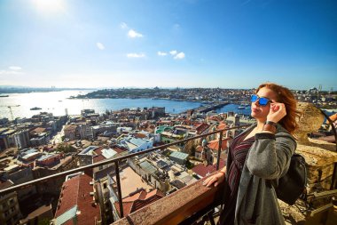 Güzel bir turist kız Galata Kulesi 'nin tepesinden İstanbul' un tarihi merkezinin manzarasının keyfini çıkarıyor.