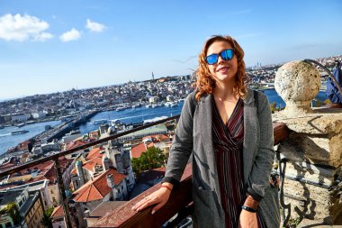 Güzel bir turist kız Galata Kulesi 'nin tepesinden İstanbul' un tarihi merkezinin manzarasının keyfini çıkarıyor.