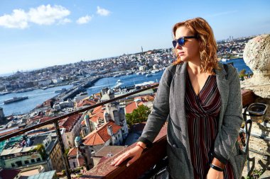 Güzel bir turist kız Galata Kulesi 'nin tepesinden İstanbul' un tarihi merkezinin manzarasının keyfini çıkarıyor.