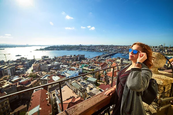 Güzel bir turist kız Galata Kulesi 'nin tepesinden İstanbul' un tarihi merkezinin manzarasının keyfini çıkarıyor.