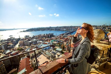 Güzel bir turist kız Galata Kulesi 'nin tepesinden İstanbul' un tarihi merkezinin manzarasının keyfini çıkarıyor.