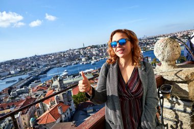 Güzel bir turist kız Galata Kulesi 'nin tepesinden İstanbul' un tarihi merkezinin manzarasının keyfini çıkarıyor.