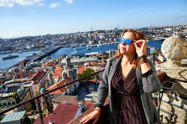 Güzel bir turist kız Galata Kulesi 'nin tepesinden İstanbul' un tarihi merkezinin manzarasının keyfini çıkarıyor.