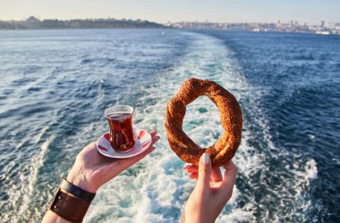 İstanbul ve Marmar Denizi 'nin arka planında bir fincan geleneksel Türk çayı (armudu) ve Simitci (susam tohumlu yuvarlak bir simit) el ele tutuştur