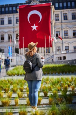 İstanbul 'daki Beyoğlu Belediye Binası' nda Türk bayrağının arka planında duran çekici genç bayan turist